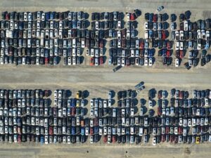 Aerial View Of Auction Reseller Company Big Parking Lot With Parked Cars Ready For Remarketing Services. Sales Of Secondhand Vehicles