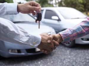 The Car Salesman Is Handing Over The Keys To The Buyer After The Lease Has Been Agreed.
