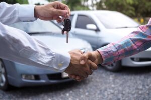 The Car Salesman Is Handing Over The Keys To The Buyer After The Lease Has Been Agreed.
